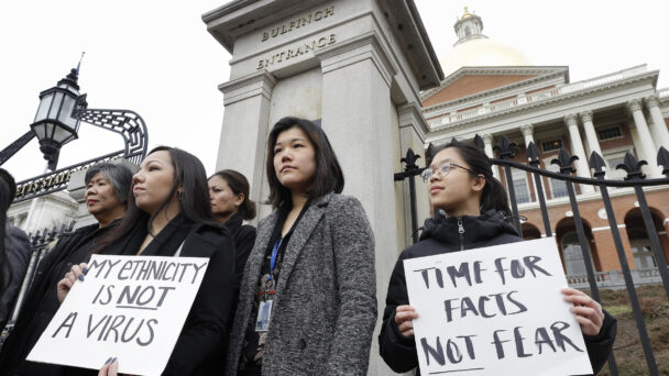 Jessica Wong, of Fall River, Mass., front left, Jenny Chiang, of Medford, Mass., center, and Sheila Vo, of Boston, from the state's Asian American Commission, stand together during a protest, Thursday, March 12, 2020, on the steps of the Statehouse in Boston. Asian American leaders in Massachusetts condemned what they say is racism, fear-mongering and misinformation aimed at Asian communities amid the widening coronavirus pandemic that originated in China. (AP Photo/Steven Senne)