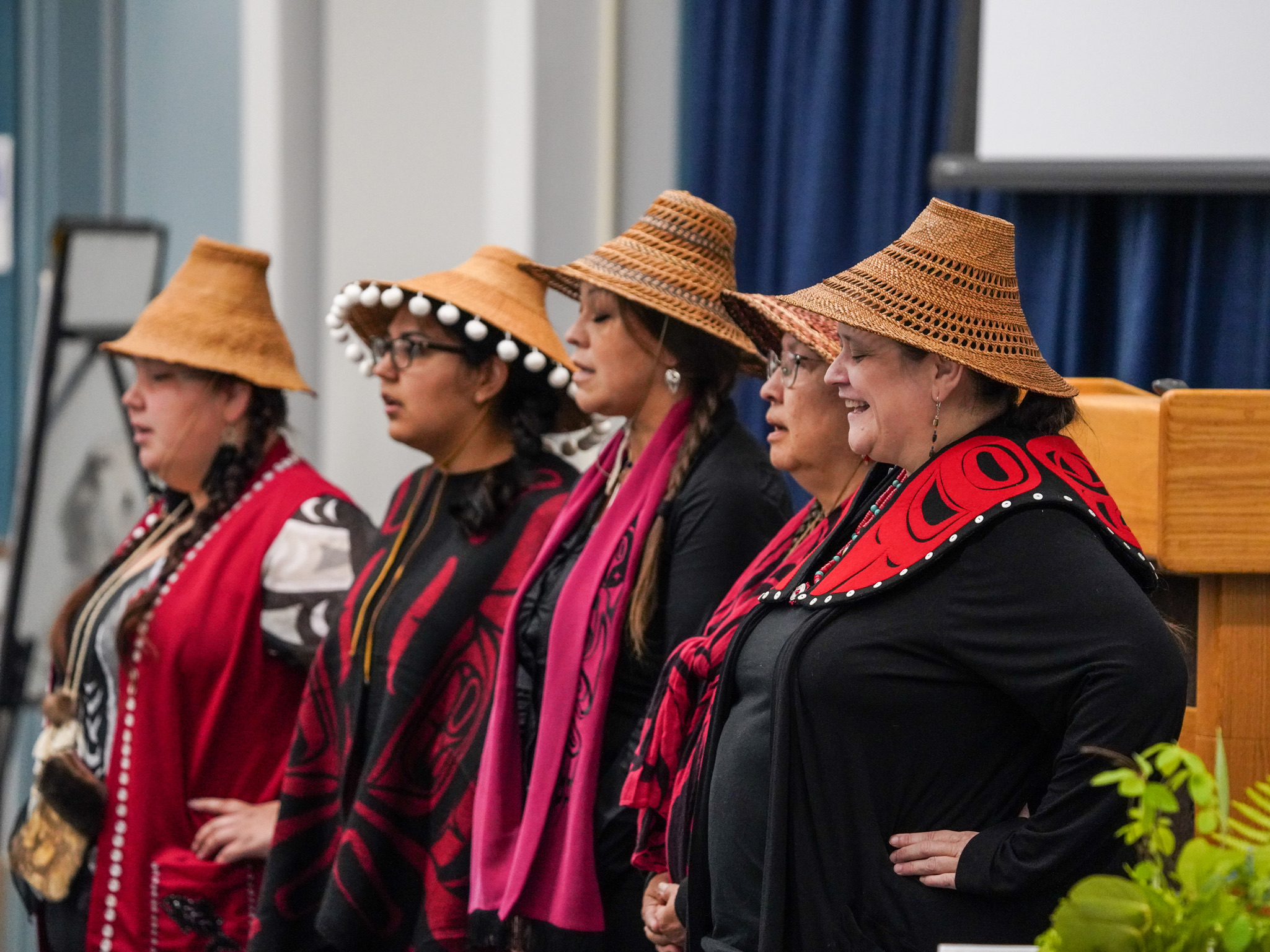 Five members of the Haida Descendants Dancers from the Saxman Clan dressed in red and black traditional native garments sing as a part of the land acknowledgement ritual.