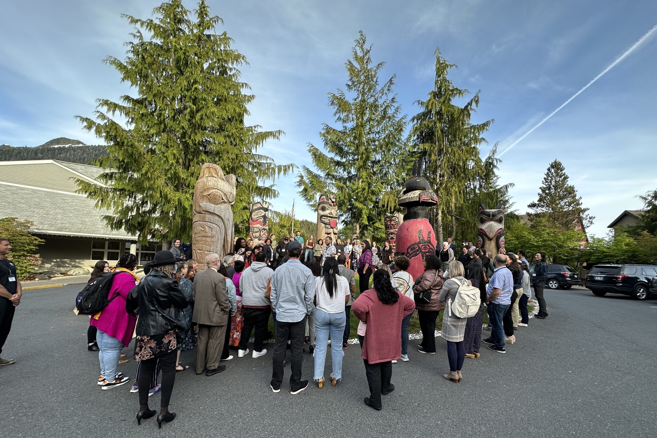 Community members, health care professionals and summit participants gather around a totem circle composed of six 10 feet totem poles outside the convening center.