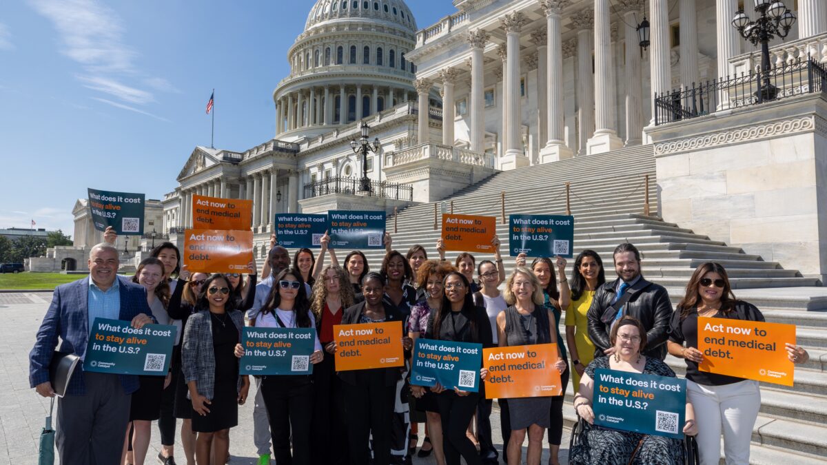 Group of community members and advocates stand in front of steps of Capitol Hill and hold signs calling for action to end medical debt