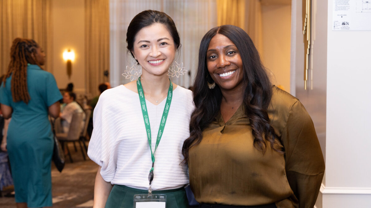 Two people pose for a photo in a conference room.