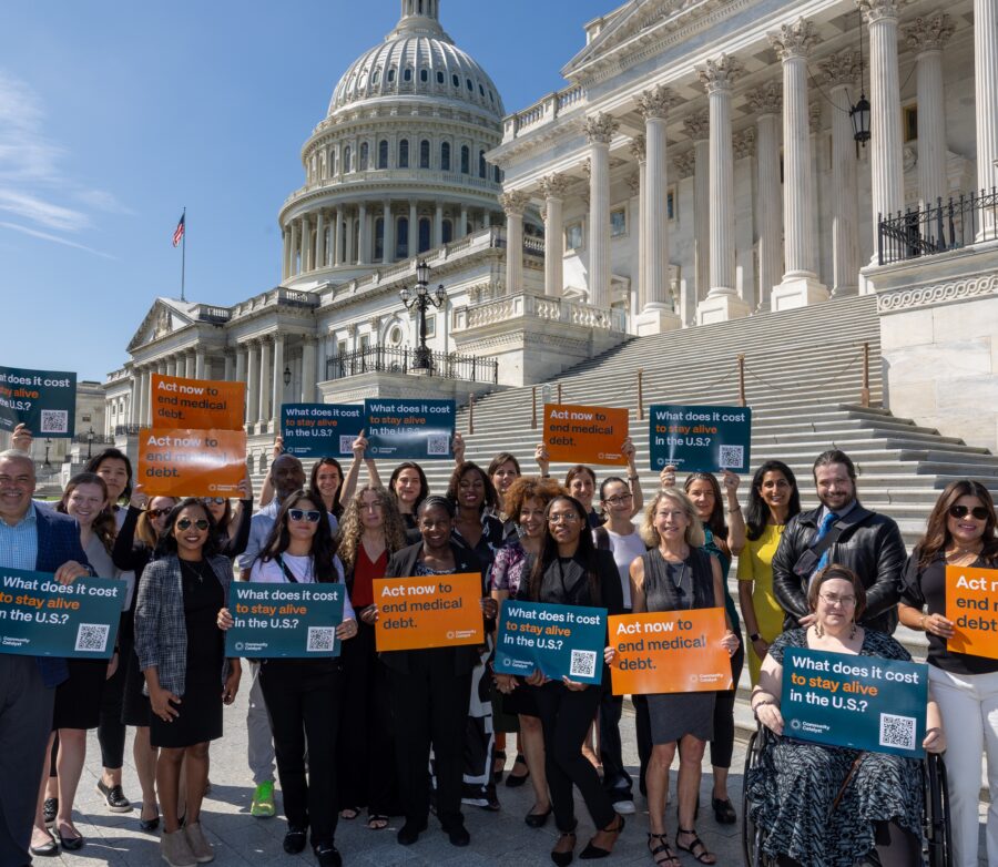 A large group of community members and advocates hold signs and pose in front of the steps of the U.S. Capitol in Washington, D.C.