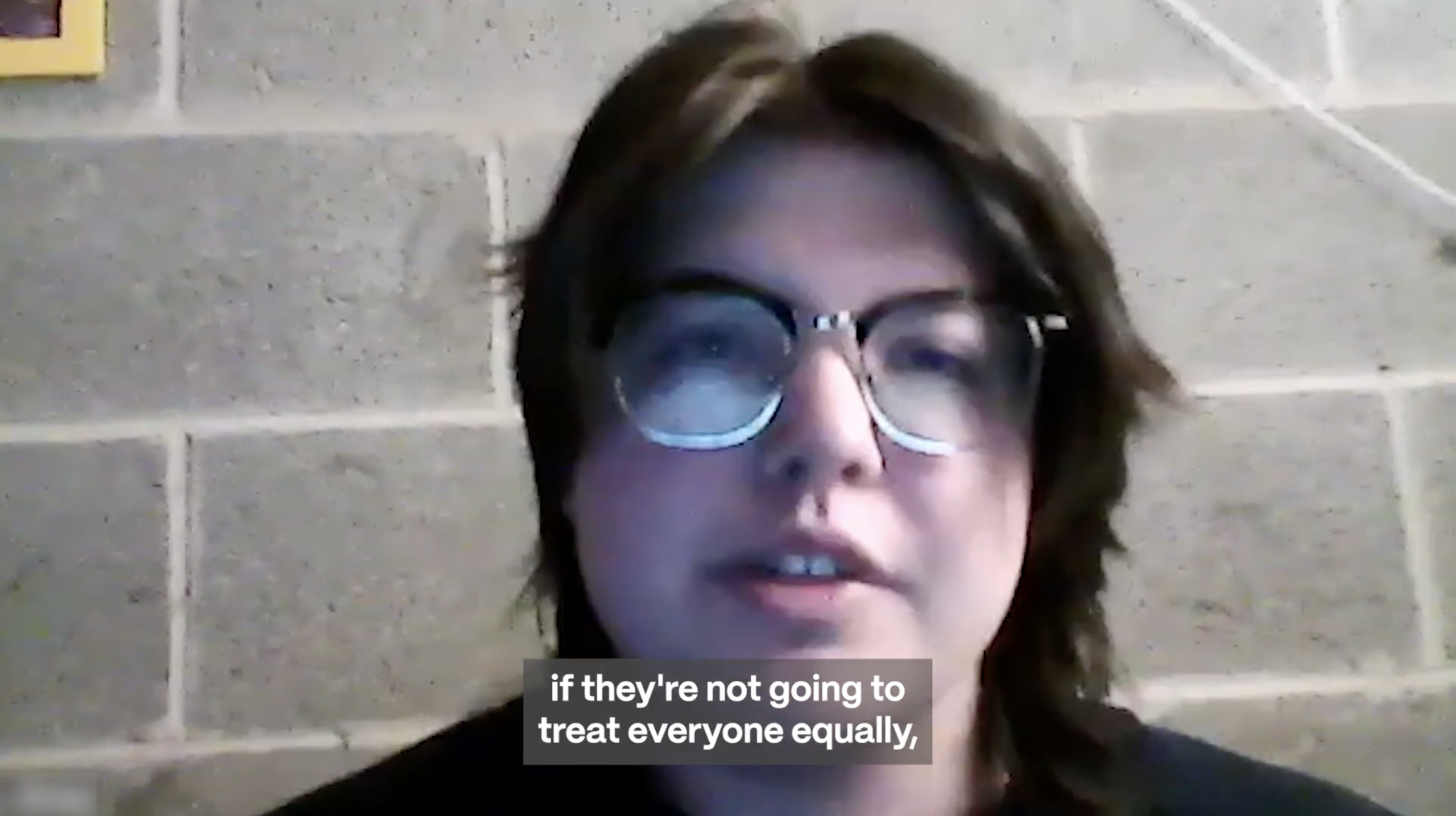 Video still of EJ speaking in front of a concrete wall. A caption at the bottom center of the image reads "if they're not going to treat everyone equally."