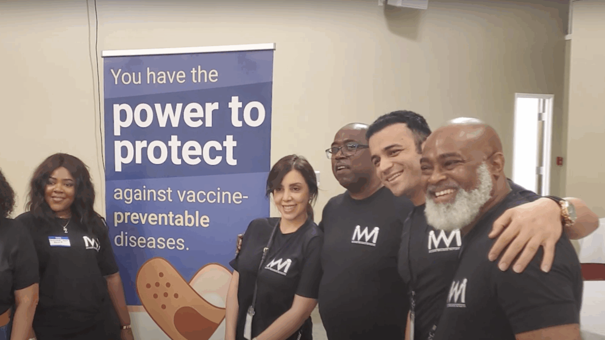 A group of five people poses near a poster that says "You have the power to protect against vaccine-preventable diseases