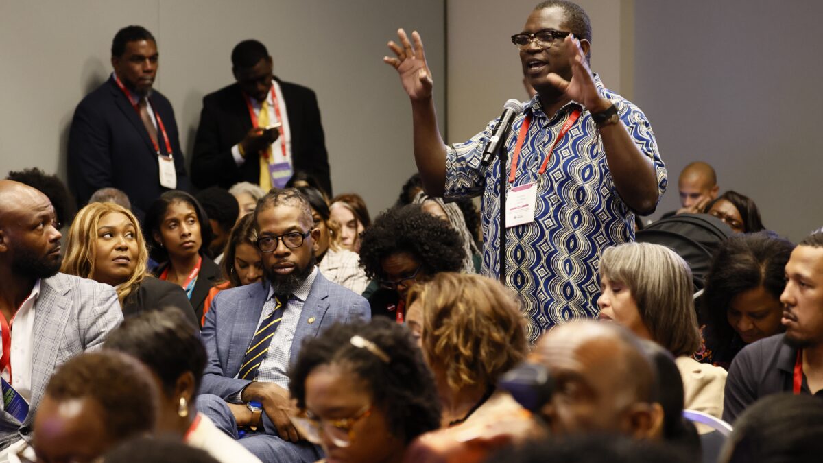 An audience member is standing in a packed room of conference attendees